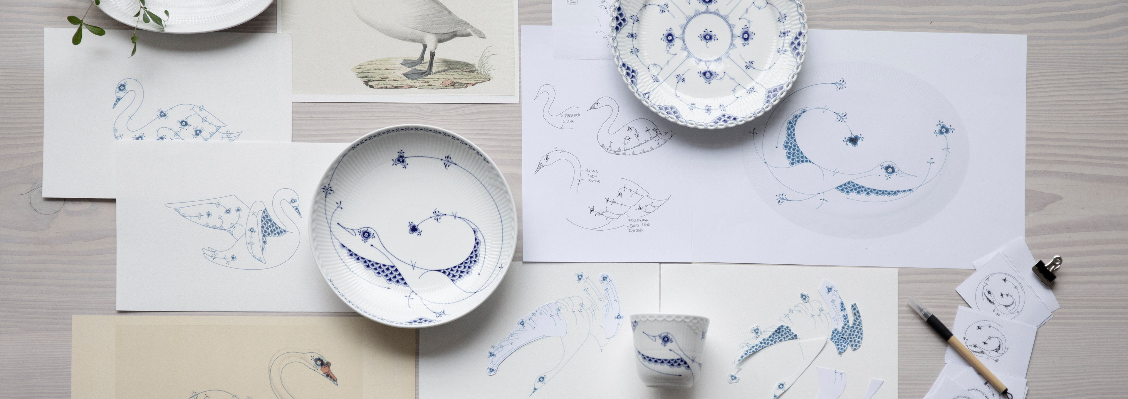 A plate from the Royal Creatures collection lying on a desk which is filled with drawings indicating the design process behind the plate and the collection